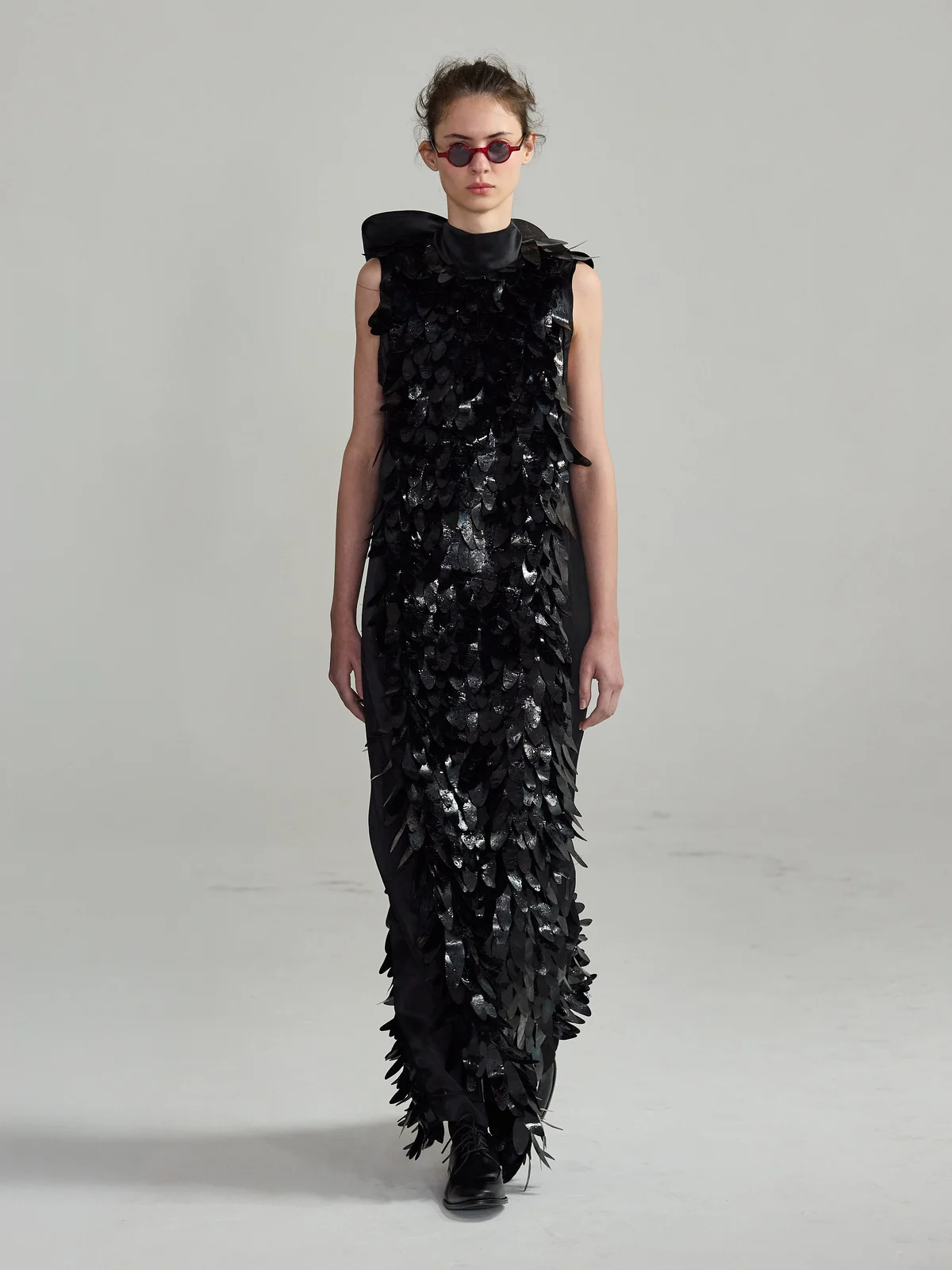 Vestido longo coberto de plumas pretas, na passarela de Augusto Paz. Foto de Zé Takahashi.